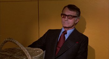 Movie still from “Bring Me the Head of Alfredo Garcia” (1974), directed by Sam Peckinpah – A man in a suit and tie standing next to a basket; Close Up shot, Low angle