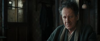 Movie still from “The Book Thief” (2013), directed by Brian Percival – An older man wearing a sweater and a tie; Close Up shot, Over the shoulder angle