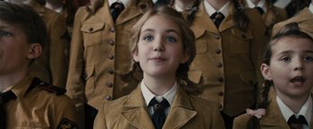 Movie still from “The Book Thief” (2013), directed by Brian Percival – A girl in a suit and tie standing in front of a group of men; Close Up shot, Over the shoulder angle