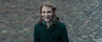 Movie still from “The Book Thief” (2013), directed by Brian Percival – A young girl in a green coat smiling for the camera; Close Up shot, Over the shoulder angle