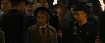 Movie still from “The Book Thief” (2013), directed by Brian Percival – A young girl in a trench coat and a hat; Close Up shot, Over the shoulder angle