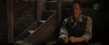 Movie still from “The Book Thief” (2013), directed by Brian Percival – An older man sitting in a chair next to a wooden staircase; Medium shot, High angle