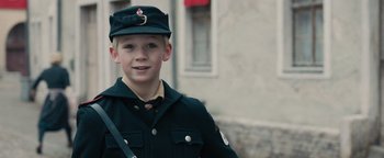 Movie still from “The Book Thief” (2013), directed by Brian Percival – A young boy in a military uniform is smiling for the camera; Close Up shot, Over the shoulder angle