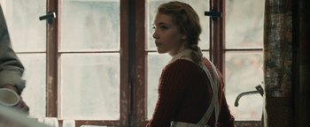 Movie still from “The Book Thief” (2013), directed by Brian Percival – A woman in a red sweater standing in front of a window; Medium shot, Over the shoulder angle