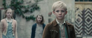 Movie still from “The Book Thief” (2013), directed by Brian Percival – A boy and a girl standing next to each other in front of a building; Close Up shot, Low angle