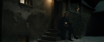 Movie still from “The Book Thief” (2013), directed by Brian Percival – A man sitting on steps holding an accordion; Wide shot, Low angle