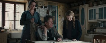 Movie still from “The Book Thief” (2013), directed by Brian Percival – A man sitting at a table next to two other people; Medium shot, Low angle