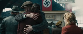 Movie still from “The Book Thief” (2013), directed by Brian Percival – A man and a woman hug in front of a nazi flag; Medium shot, Over the shoulder angle