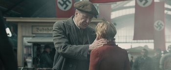 Movie still from “The Book Thief” (2013), directed by Brian Percival – An older man and a younger woman are touching each other; Medium shot, Over the shoulder angle