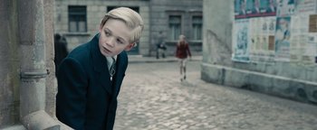 Movie still from “The Book Thief” (2013), directed by Brian Percival – A boy and a girl walking down a street; Medium shot, Over the shoulder angle