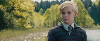 Movie still from “The Book Thief” (2013), directed by Brian Percival – A young boy in a sweater and a tie in front of a body of water; Close Up shot, Over the shoulder angle