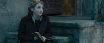 Movie still from “The Book Thief” (2013), directed by Brian Percival – A young girl sitting on steps reading a book; Close Up shot, Over the shoulder angle