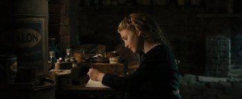 Movie still from “The Book Thief” (2013), directed by Brian Percival – A young girl writing on a piece of paper; Medium shot, Over the shoulder angle