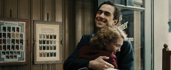 Movie still from “The Book Thief” (2013), directed by Brian Percival – A man and a woman smiling for the camera; Medium shot, Over the shoulder angle