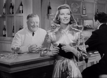 Movie still from “Bringing Up Baby” (1938), directed by Howard Hawks – An old black and white photo of a man and a woman at a bar; Medium shot, Low angle