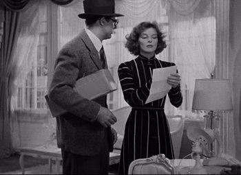 Movie still from “Bringing Up Baby” (1938), directed by Howard Hawks – A man and a woman standing next to each other holding papers; Medium shot, Over the shoulder angle
