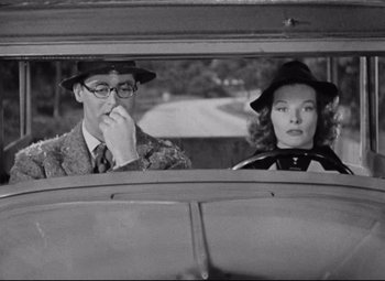 Movie still from “Bringing Up Baby” (1938), directed by Howard Hawks – A man and a woman sitting in the back seat of a car; Medium shot, Over the shoulder angle