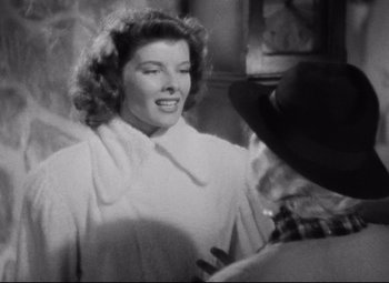 Movie still from “Bringing Up Baby” (1938), directed by Howard Hawks – A black - and - white photo of a woman smiling; Medium shot, Over the shoulder angle