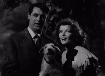 Movie still from “Bringing Up Baby” (1938), directed by Howard Hawks – A man and a woman standing next to a dog; Medium shot, Low angle