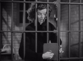 Movie still from “Bringing Up Baby” (1938), directed by Howard Hawks – A black and white photo of a woman in a jail cell; Medium shot, Low angle