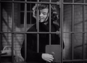 Movie still from “Bringing Up Baby” (1938), directed by Howard Hawks – A black and white photo of a woman in a jail cell; Medium shot, Low angle