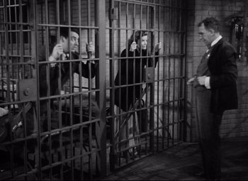 Movie still from “Bringing Up Baby” (1938), directed by Howard Hawks – A group of people sitting inside of a jail cell; Wide shot, High angle