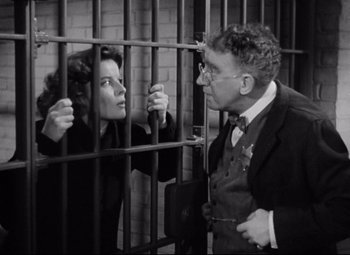 Movie still from “Bringing Up Baby” (1938), directed by Howard Hawks – An old photo of a man and a woman behind a fence; Medium shot, Low angle