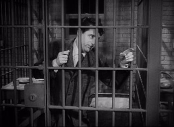 Movie still from “Bringing Up Baby” (1938), directed by Howard Hawks – An old photo of a man sitting in a jail cell; Medium shot, High angle