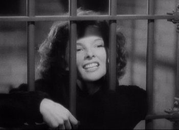 Movie still from “Bringing Up Baby” (1938), directed by Howard Hawks – A black - and - white photo of a woman behind bars; Medium shot, Low angle