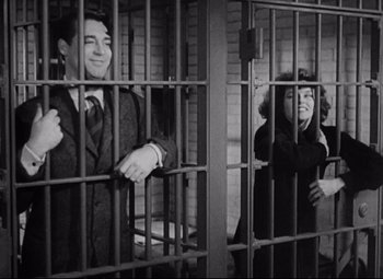 Movie still from “Bringing Up Baby” (1938), directed by Howard Hawks – A man and a woman standing behind bars in a jail cell; Medium shot, Low angle