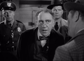 Movie still from “Bringing Up Baby” (1938), directed by Howard Hawks – An old photo of a man in a suit and tie; Medium shot, Over the shoulder angle