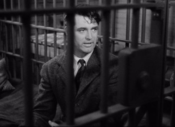 Movie still from “Bringing Up Baby” (1938), directed by Howard Hawks – A black and white photo of a man in a suit behind bars; Close Up shot, Low angle