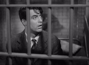 Movie still from “Bringing Up Baby” (1938), directed by Howard Hawks – A man in a suit sitting in front of a jail cell; Medium shot, Low angle