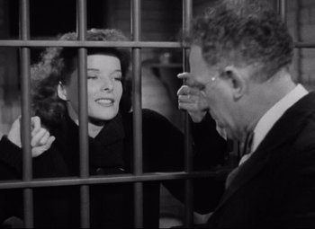 Movie still from “Bringing Up Baby” (1938), directed by Howard Hawks – An old photo of a man and a woman behind bars; Medium shot, Low angle