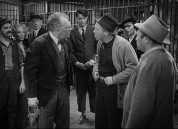 Movie still from “Bringing Up Baby” (1938), directed by Howard Hawks – A black and white photo of a group of men talking to each other; Medium shot, Over the shoulder angle