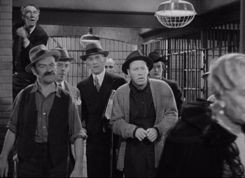 Movie still from “Bringing Up Baby” (1938), directed by Howard Hawks – A black and white photo of a group of men standing in a jail cell; Wide shot, Low angle