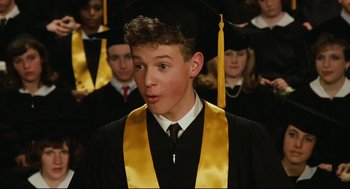 Movie still from “Broadcast News” (1987), directed by James L. Brooks – A young man in a graduation cap and gown; Close Up shot, High angle