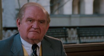 Movie still from “Broadcast News” (1987), directed by James L. Brooks – An older man wearing a suit and tie; Close Up shot, Low angle