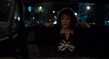 Movie still from “Broadcast News” (1987), directed by James L. Brooks – A woman sitting in the back seat of a car at night; Medium shot, Over the shoulder angle
