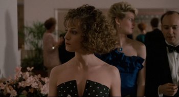 Movie still from “Broadcast News” (1987), directed by James L. Brooks – A woman with curly brown hair wearing a black and white dress; Medium shot, Over the shoulder angle