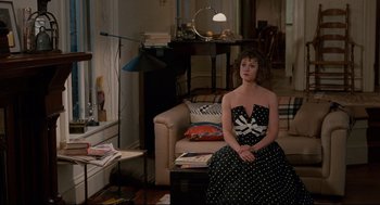 Movie still from “Broadcast News” (1987), directed by James L. Brooks – A woman sitting on a couch in a living room; Wide shot, High angle