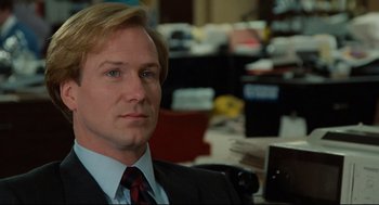 Movie still from “Broadcast News” (1987), directed by James L. Brooks – A man in a suit and tie sitting in an office chair; Close Up shot, Over the shoulder angle
