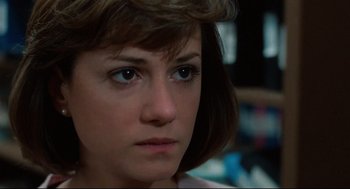 Movie still from “Broadcast News” (1987), directed by James L. Brooks – A woman's face in a dark room; Close Up shot, Over the shoulder angle