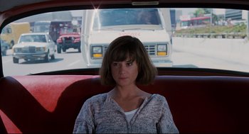 Movie still from “Broadcast News” (1987), directed by James L. Brooks – A woman sitting in the back seat of a vehicle; Medium shot, Over the shoulder angle
