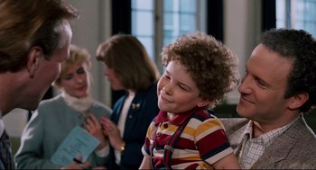 Movie still from “Broadcast News” (1987), directed by James L. Brooks – A young boy smiles as he looks at a woman; Medium shot, Over the shoulder angle