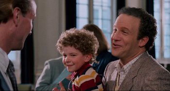 Movie still from “Broadcast News” (1987), directed by James L. Brooks – A man and a boy smiling for the camera; Close Up shot, Over the shoulder angle