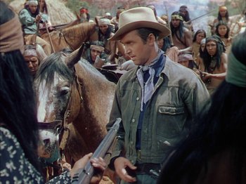 Movie still from “Broken Arrow” (1950), directed by Delmer Daves – A man with a gun standing next to a horse; Medium shot, Over the shoulder angle