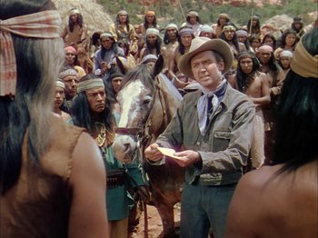 Movie still from “Broken Arrow” (1950), directed by Delmer Daves – A man standing next to a group of people; Medium shot, Over the shoulder angle