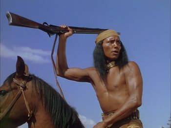 Movie still from “Broken Arrow” (1950), directed by Delmer Daves – A man holding a rifle over his shoulder while standing next to a horse; Medium shot, Low angle