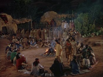 Movie still from “Broken Arrow” (1950), directed by Delmer Daves – A group of people sitting around a fire pit; Extreme Wide shot, High angle